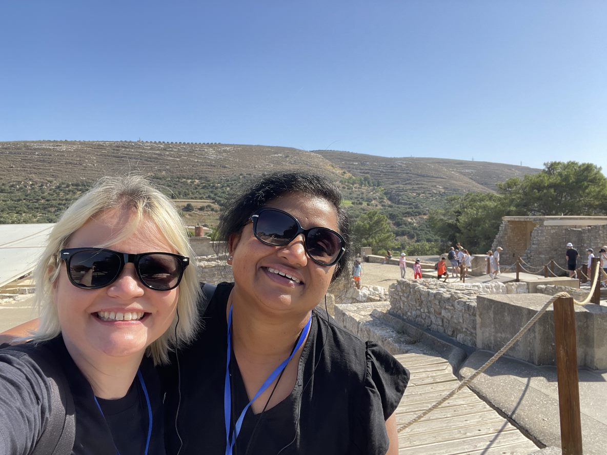 Cass and Jayashree in front of the Greek countryside