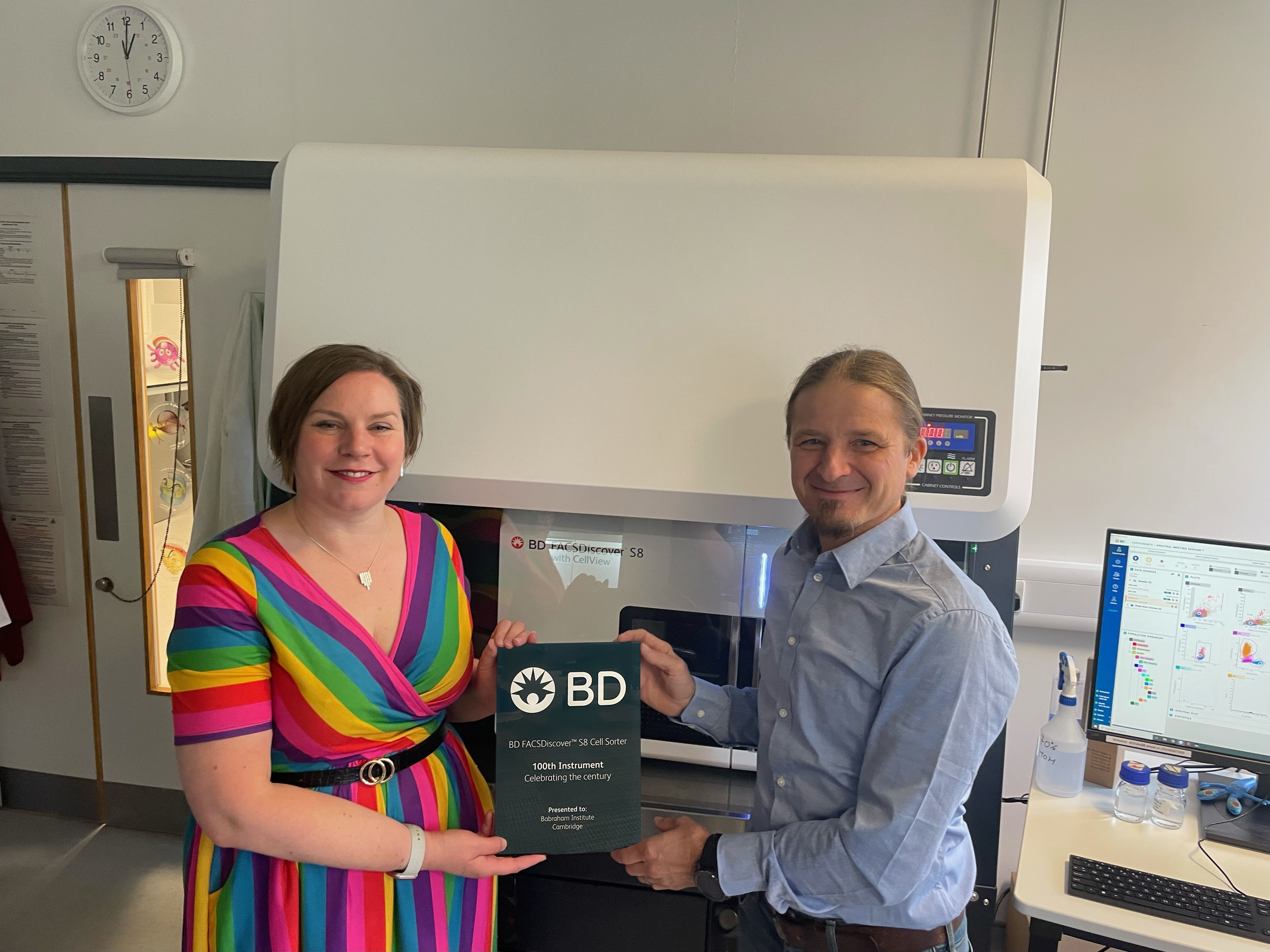 The photo shows Facility Head, Dr Rachael Walker, with Dr Aaron Tyznik, BD with the100th BD FACSDiscover S8 Spectral Sorter and a commemorative plaque. 