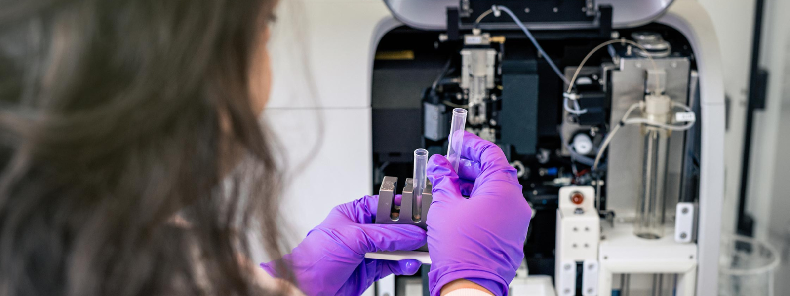 A technical specialist places a sample into a flow cytometer